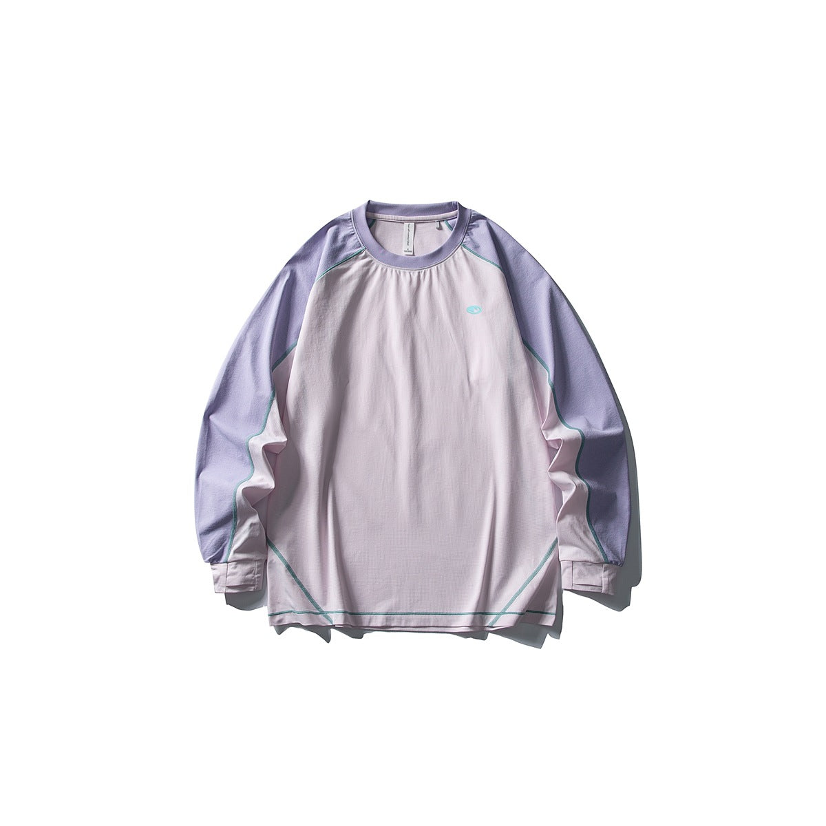 Front view of a pale pink long-sleeve crewneck top with lavender sleeves and teal seam piping, laid flat on white.