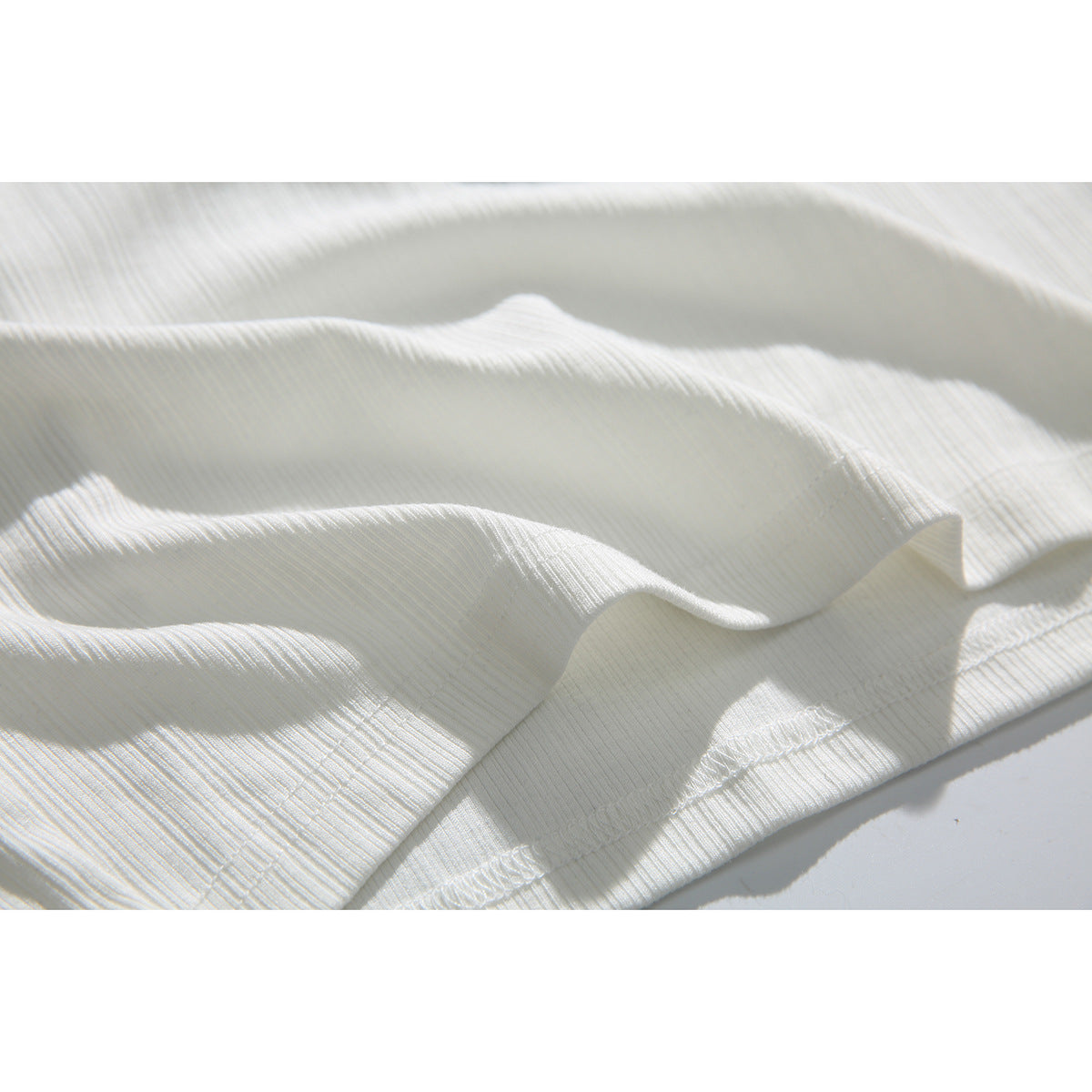 Close-up of the off-white shirt’s ribbed fabric and stitched hem.