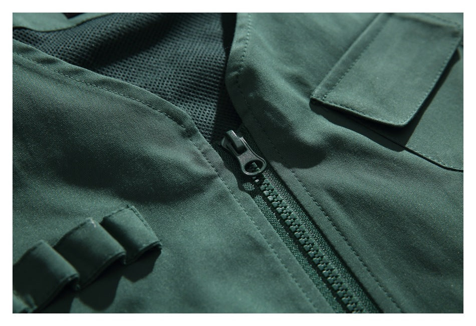 Close-up of a dark green garment's zipper, mesh lining, and rectangular flap pocket.