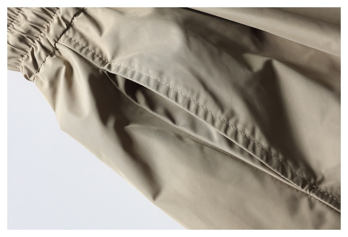 Close-up of beige trousers showing a stitched seam and gathered waistband edge.