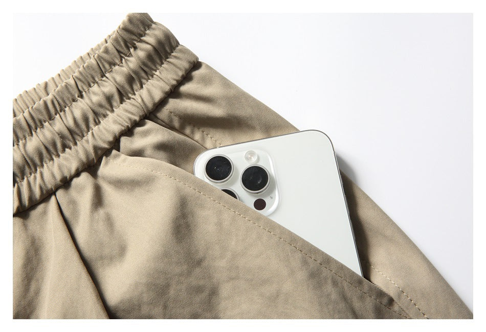 Close-up of a khaki shorts pocket holding a white smartphone.
