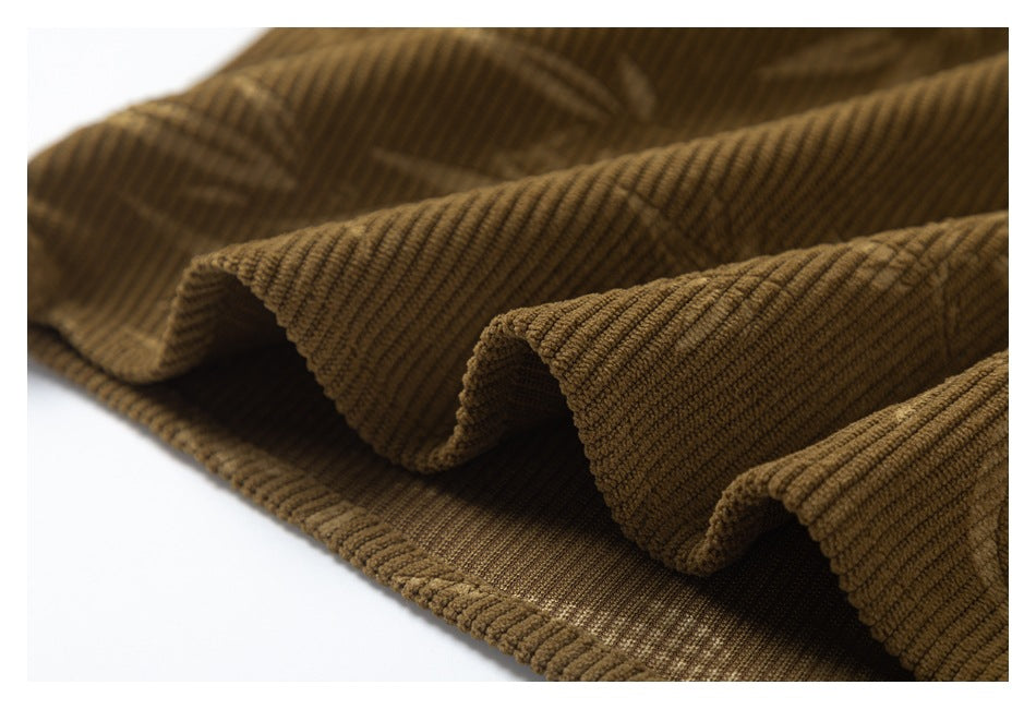 Draped brown corduroy shirt fabric showing broad ribs and a subtle geometric pattern.
