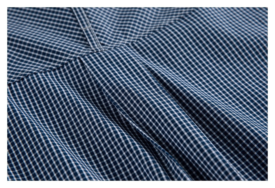 Close-up of navy-and-white checked shirt fabric with a stitched seam and folds.