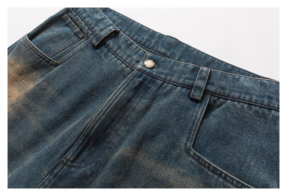 Close-up of the front waistband, button, belt loops and pockets on faded blue jeans.