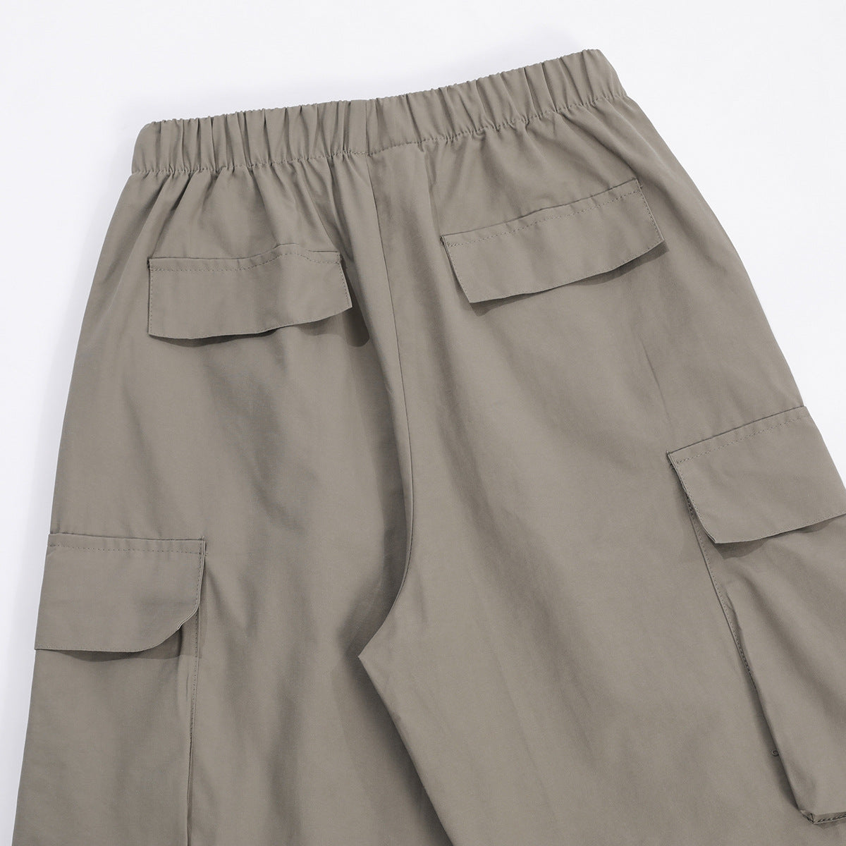 Back view of taupe-gray wide-leg cargo pants with an elastic waistband and flap pockets.