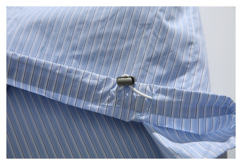 Interior close-up of a light blue striped shirt with a small black fastener at the seam.