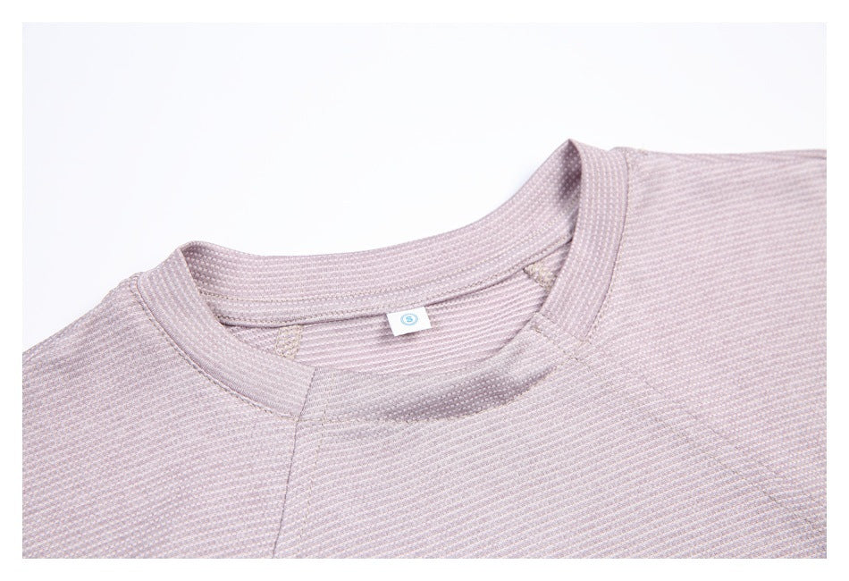 Close-up of the pale mauve shirt's ribbed crew neck, inner size tag, and patterned fabric.