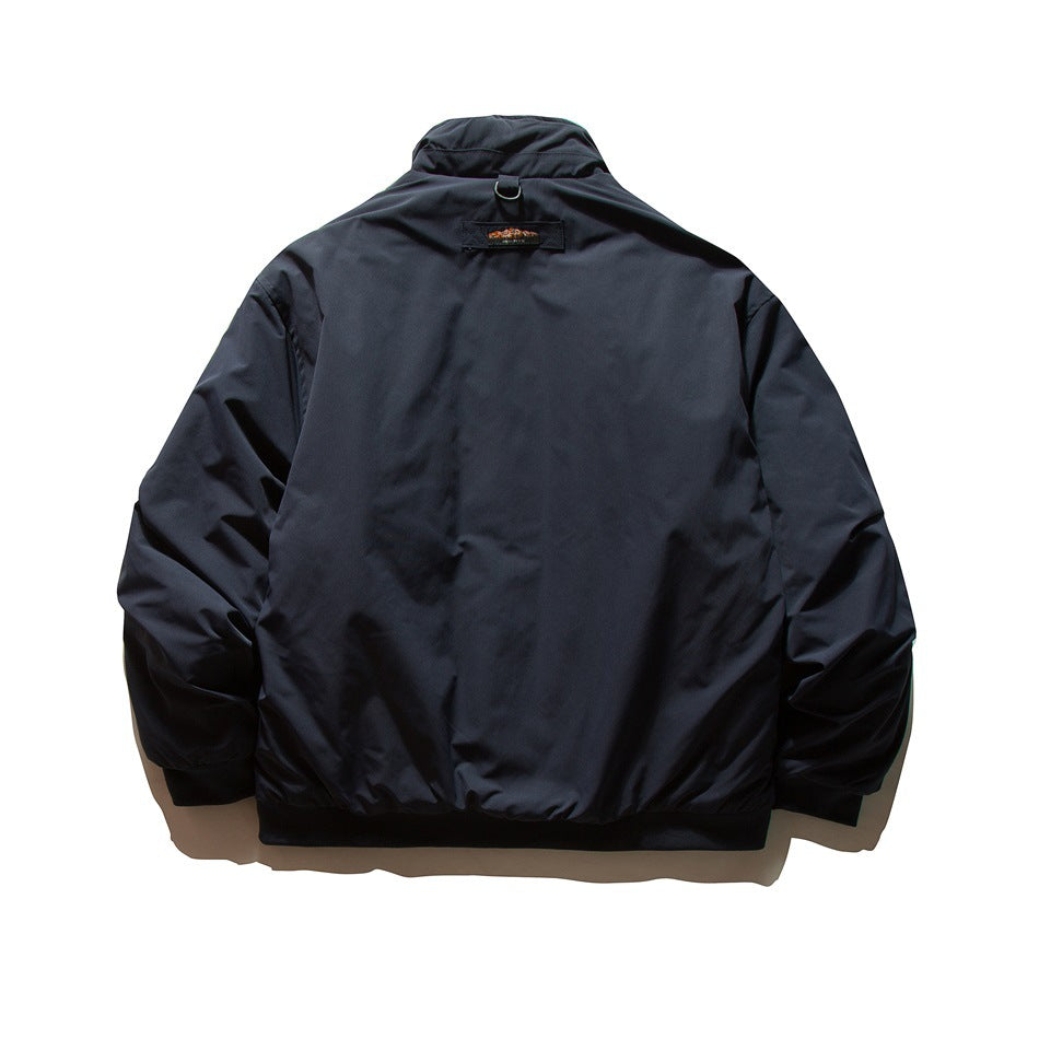 Back view of a dark navy jacket with a stand collar, elastic cuffs and hem, and a small patch below the collar.