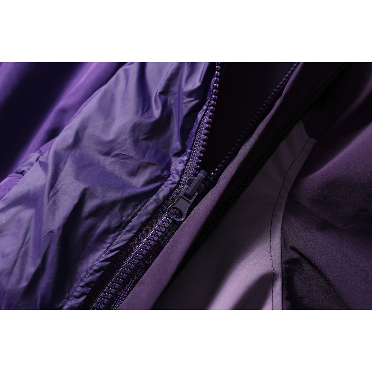Close-up of a purple jacket's front zipper and surrounding fabric.