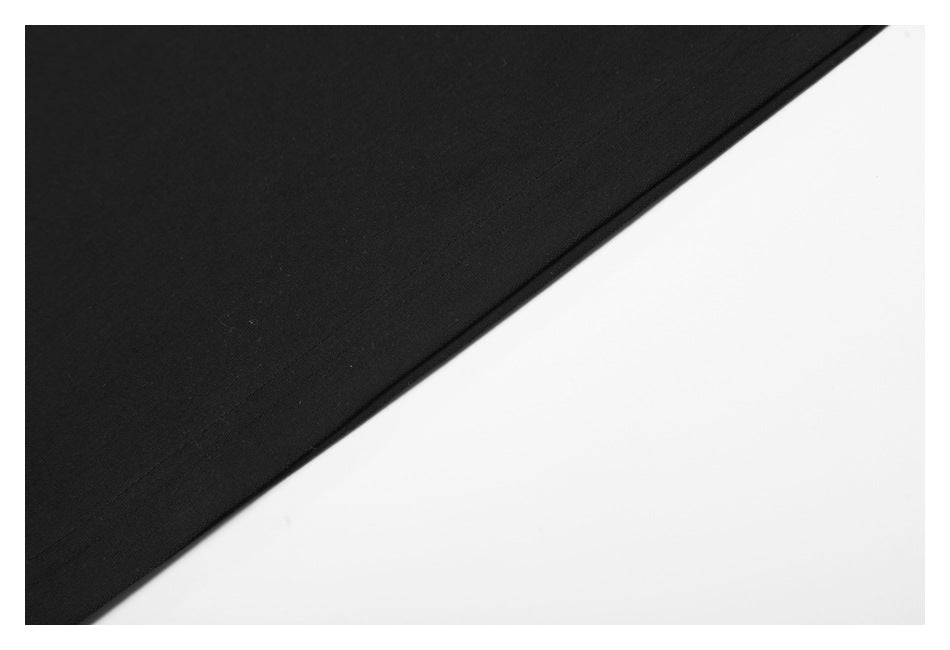Close-up of a black garment's smooth fabric and stitched edge against a white background.