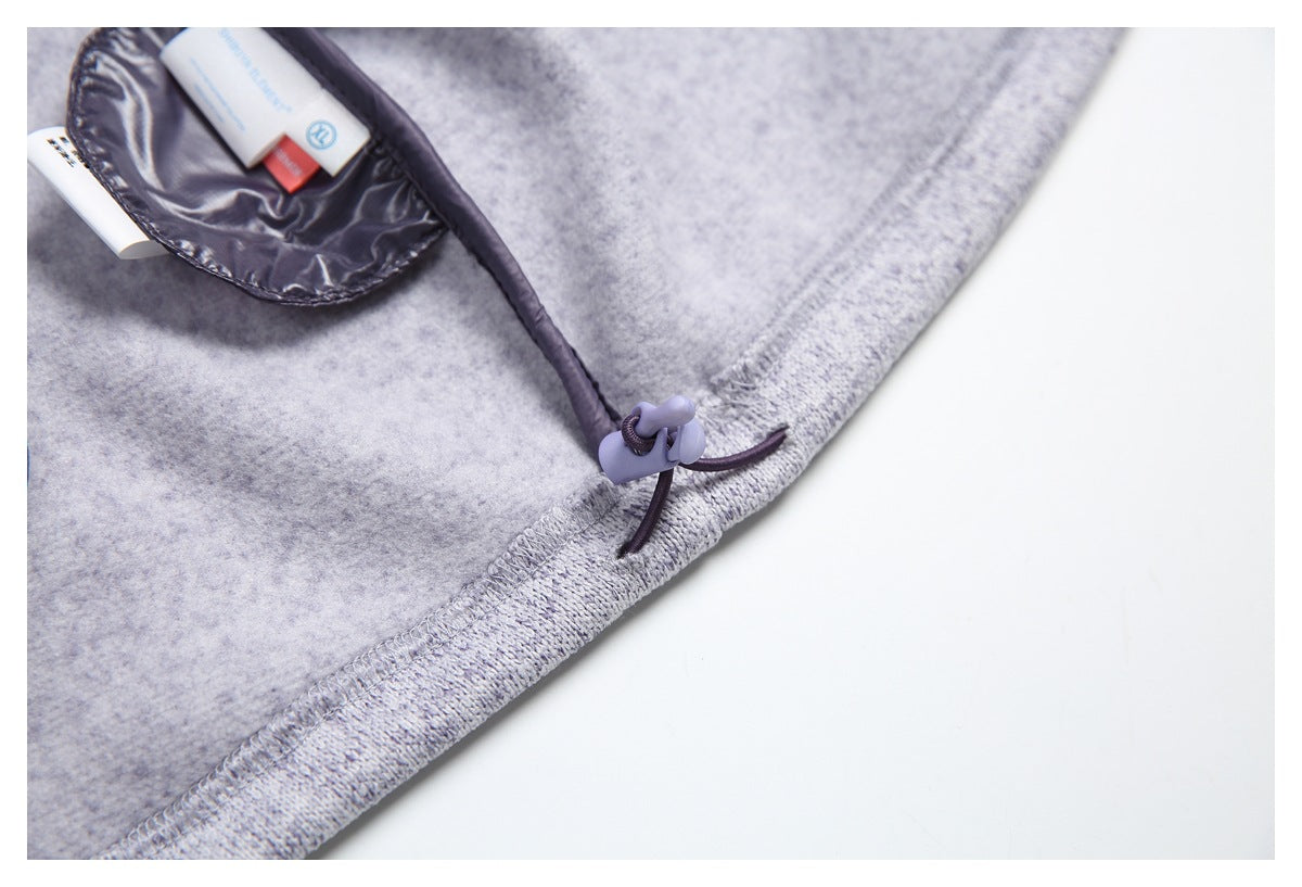 Close-up of a light gray garment interior with a dark drawcord and toggle at the stitched edge.