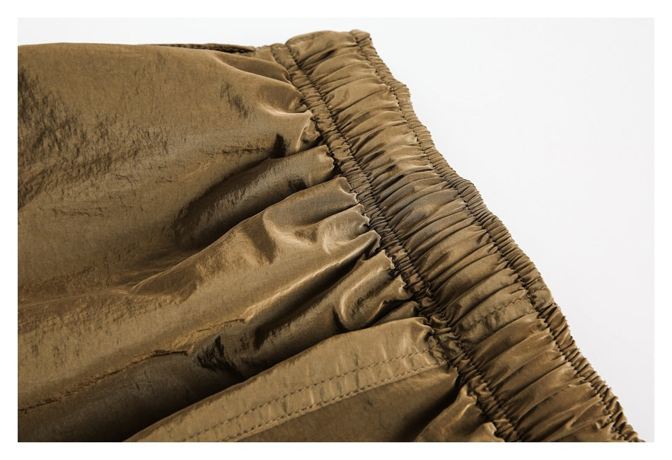 Close-up of the brown trousers' gathered elastic waistband and stitched fabric.