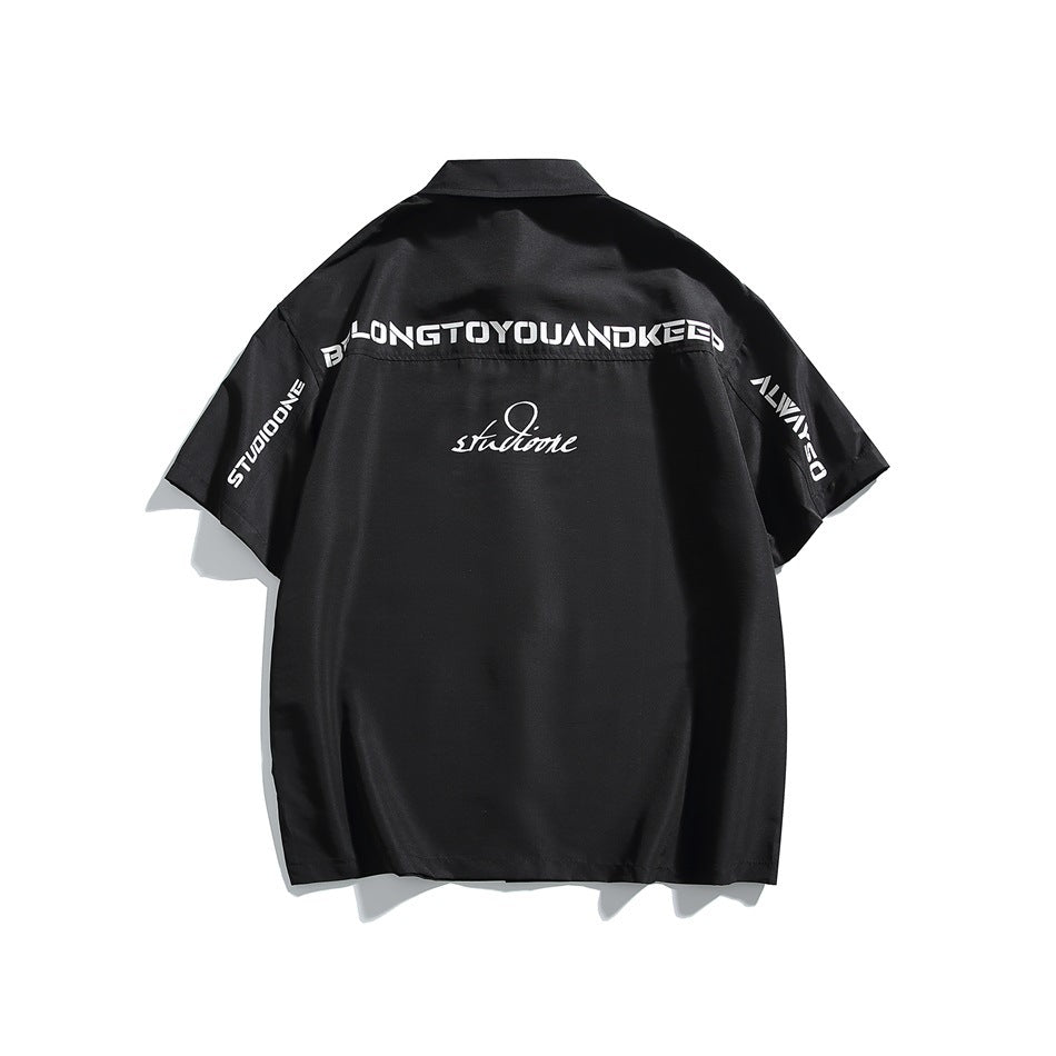 Black short-sleeve shirt back view with white block lettering across the upper back and sleeves and script graphic