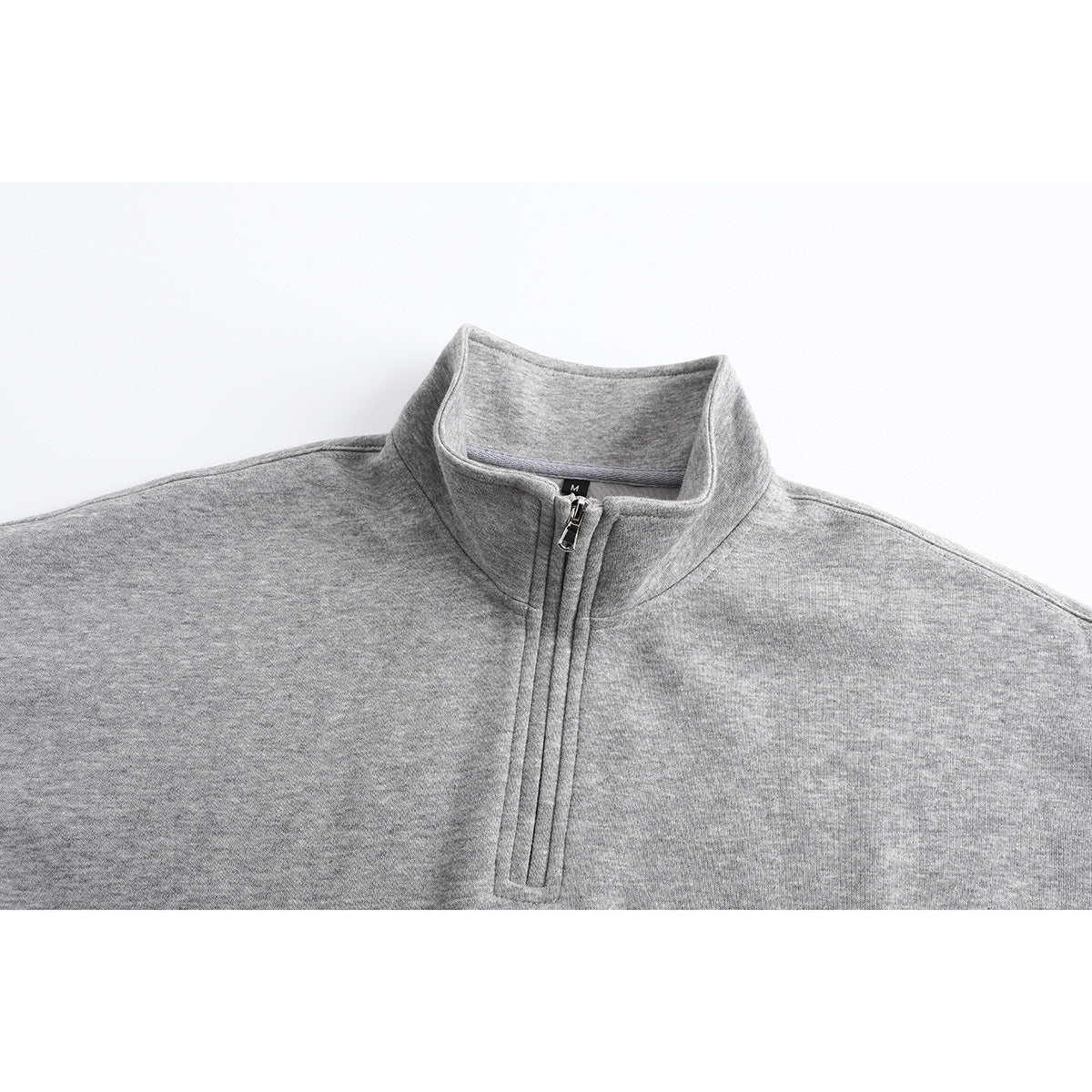 Close-up of a heather gray quarter-zip sweatshirt showing its stand collar and zipper.