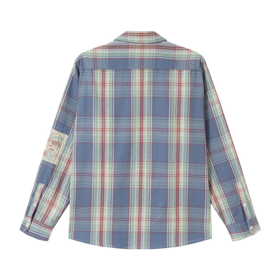 Back view of a blue plaid long-sleeve button-up shirt with a floral patch on one sleeve.