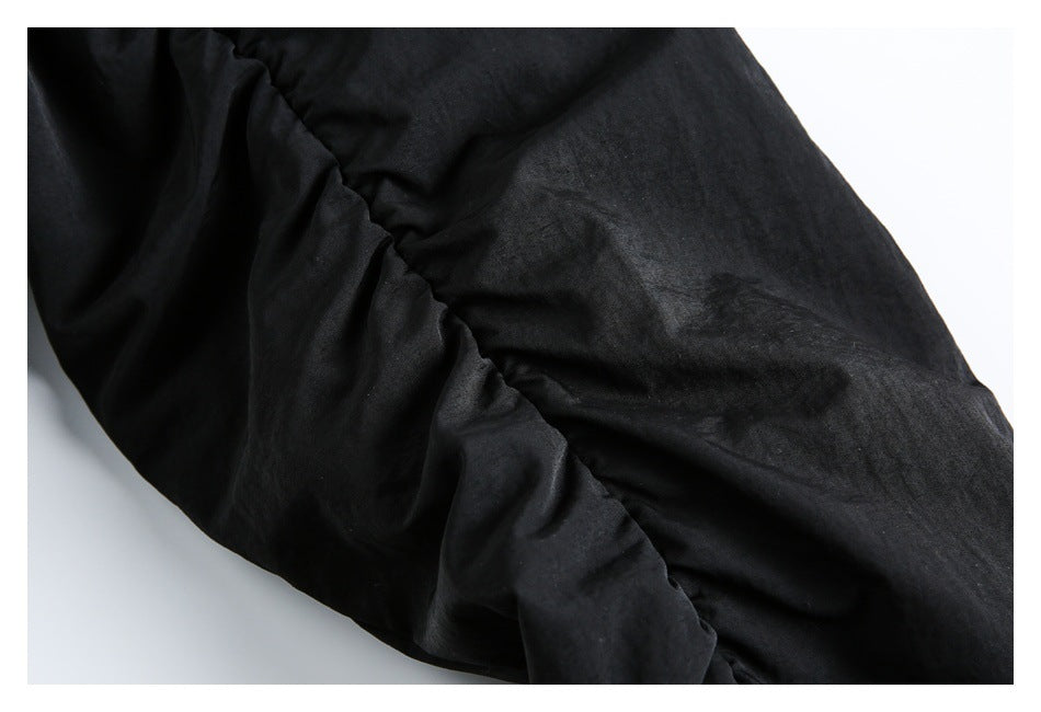 Close-up of gathered black jacket fabric and a stitched seam.