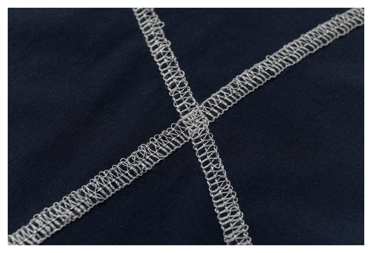 Macro view of intersecting gray overlock seams on navy fabric.
