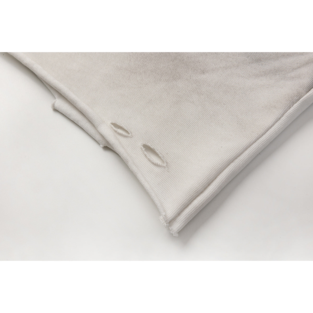Close-up of a pale gray T-shirt hem with two small distressed slits and ribbed fabric.