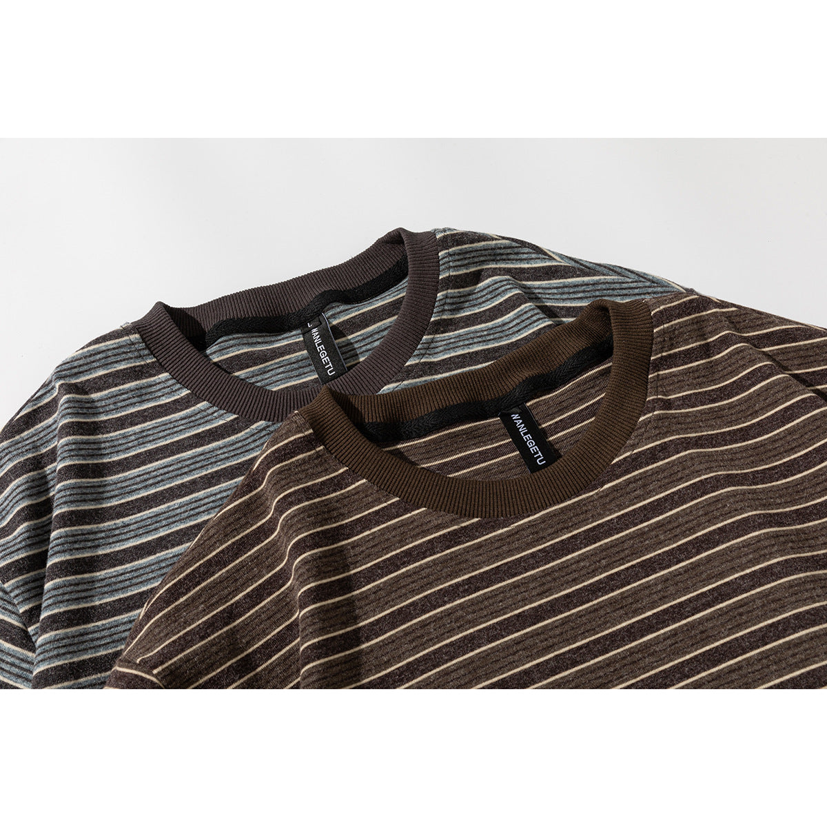 Close-up of two striped T-shirts showing ribbed crew necks in brown and blue-gray colorways.