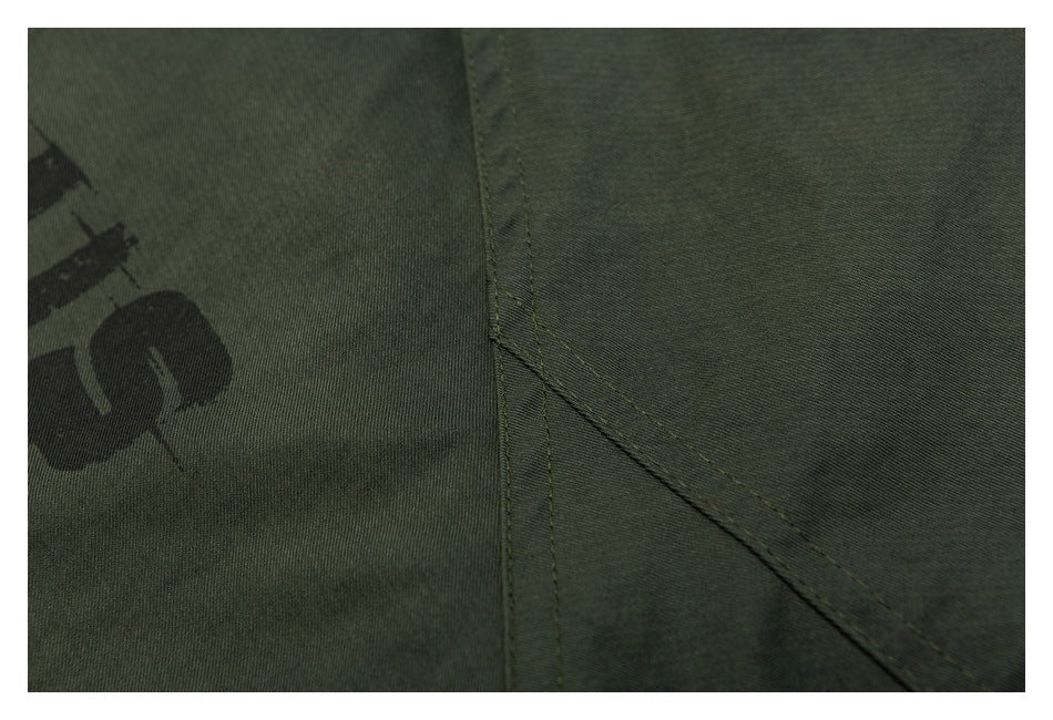 Close-up of stitching and a curved panel seam on olive green jacket fabric.
