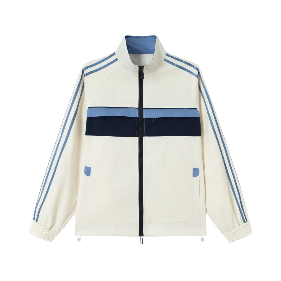 Cream zip-up track jacket with blue sleeve stripes, blue and navy chest band, stand collar and elastic cuffs