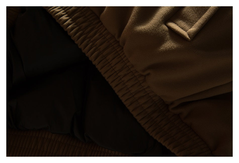 Dark close-up of a brown jacket with a ribbed elastic edge and black lining.