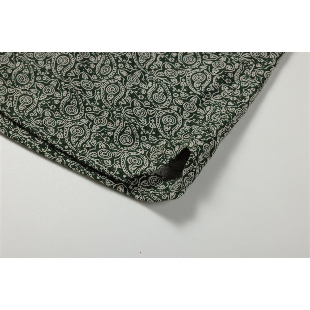Close-up of the edge and stitched opening on dark green paisley-print pants.