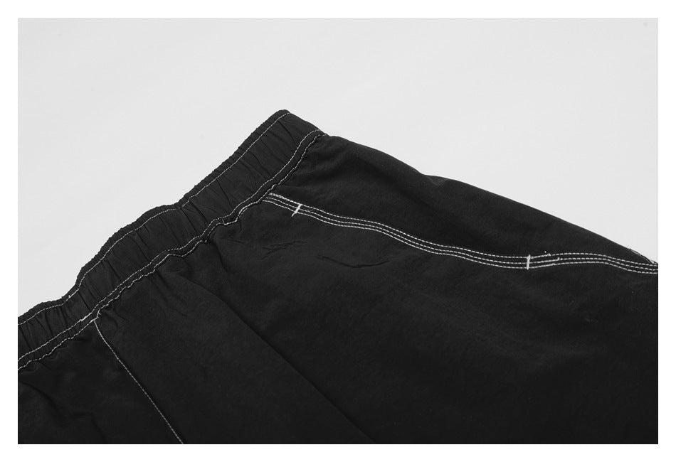 Close-up of the black trousers' elastic waistband and a white-stitched pocket seam.