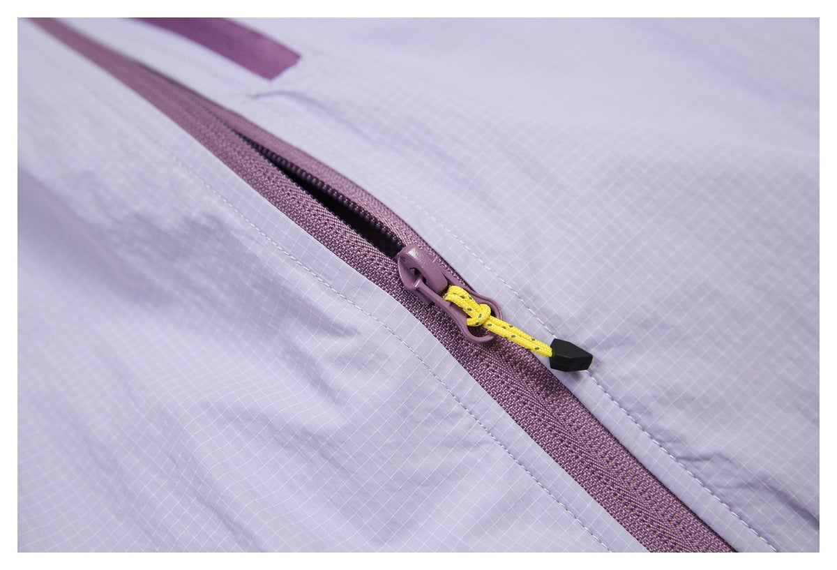 Close-up of a mauve zipper with a yellow cord pull on pale lavender grid-patterned fabric.