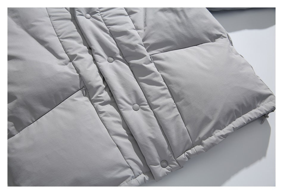 Close-up of a light gray padded jacket front with snap buttons, quilted panels and lower pockets.