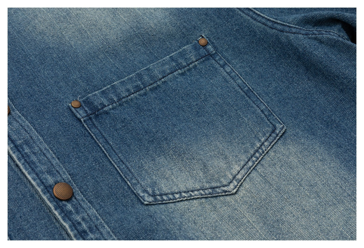 Close-up of a blue denim garment's stitched patch pocket with copper-colored rivets.