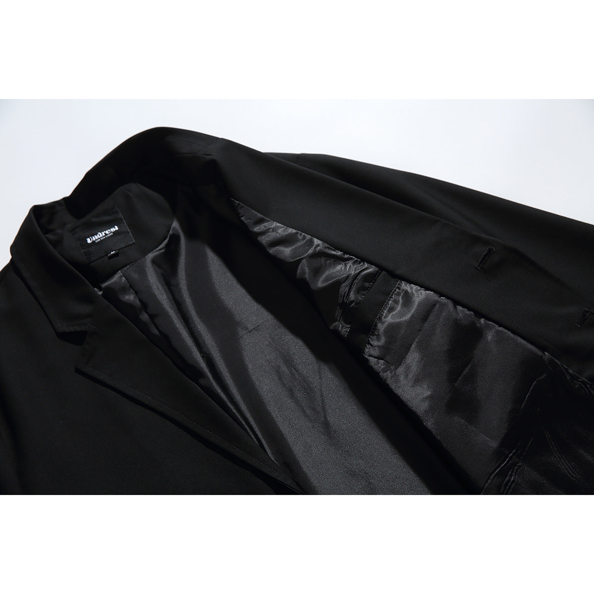 Black blazer opened to show its shiny lining and inside pocket details.