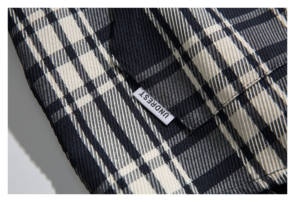 Close-up of the shirt's black, cream, and gray plaid fabric and a small woven label.
