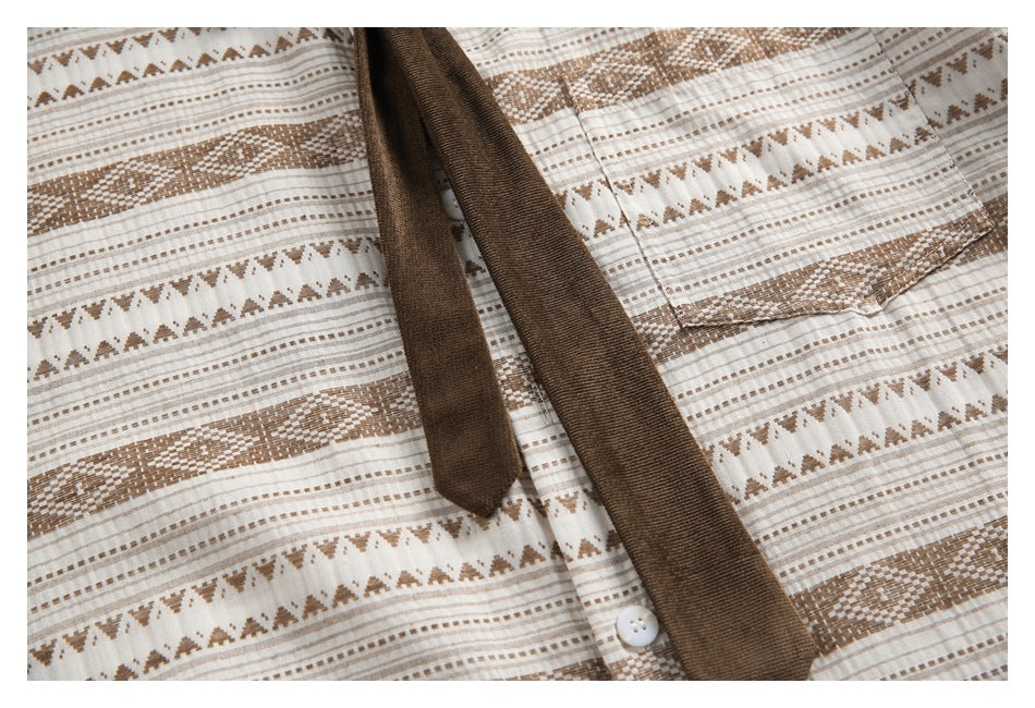 Close-up of the shirt front showing its patterned fabric, white button, and dark brown tie-like detail.