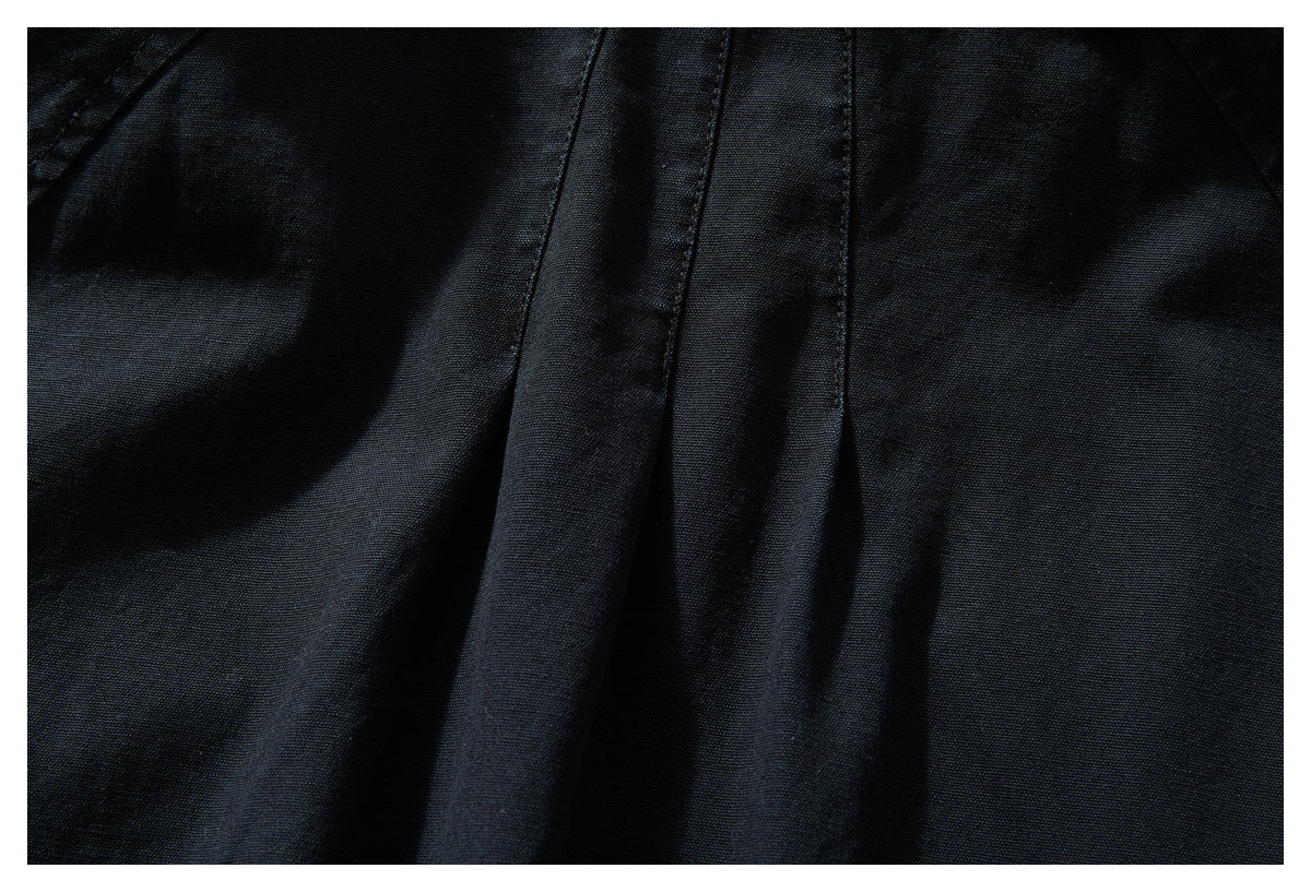 Close-up of black fabric with several vertical stitched seams and folds.