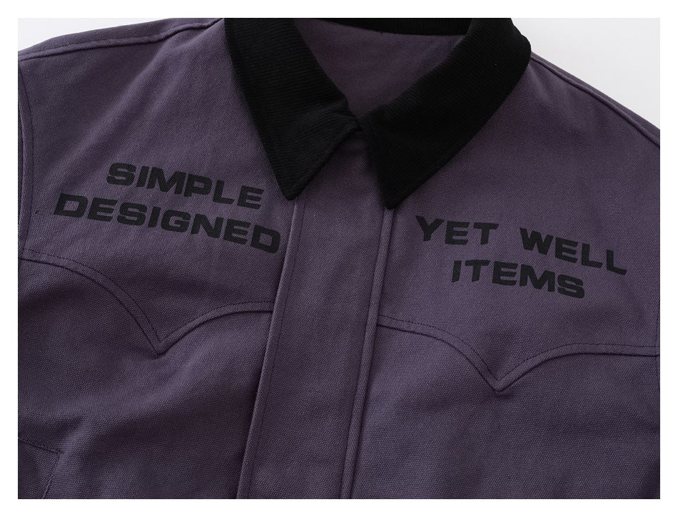 Close-up of a purple jacket's black collar, chest lettering, and curved stitched pocket details.