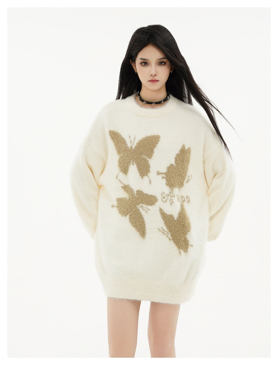 Model wearing an oversized ivory sweater dress with tan butterfly motifs and a ribbed hem.
