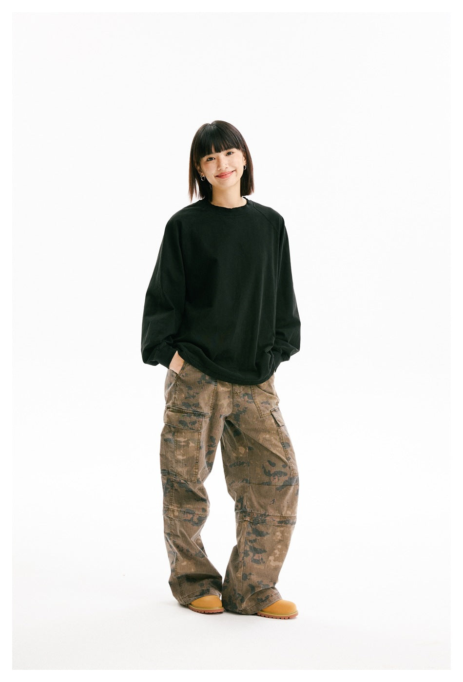 Model wearing an oversized black crewneck sweatshirt with raglan sleeves and brown camouflage cargo pants.