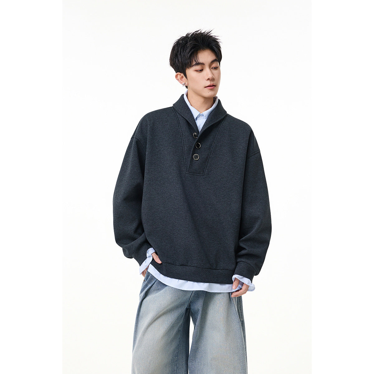 Model wearing a charcoal oversized pullover with a shawl collar and three-button placket over a pale blue shirt.