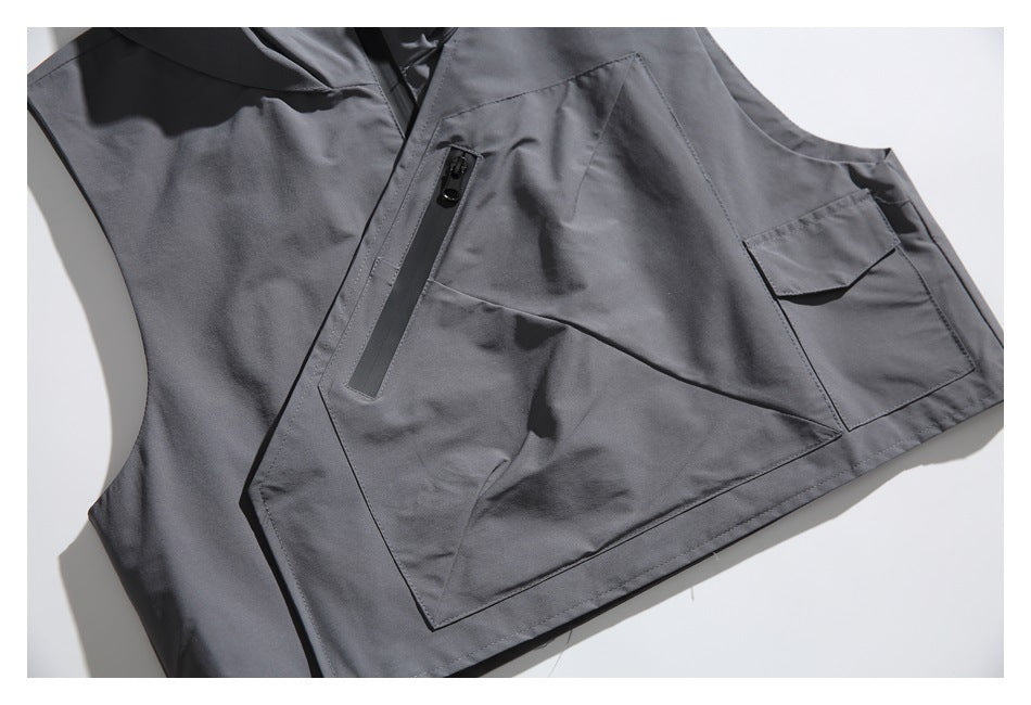 Close-up of a charcoal-gray garment front with a large angular pocket and a vertical zip pocket.