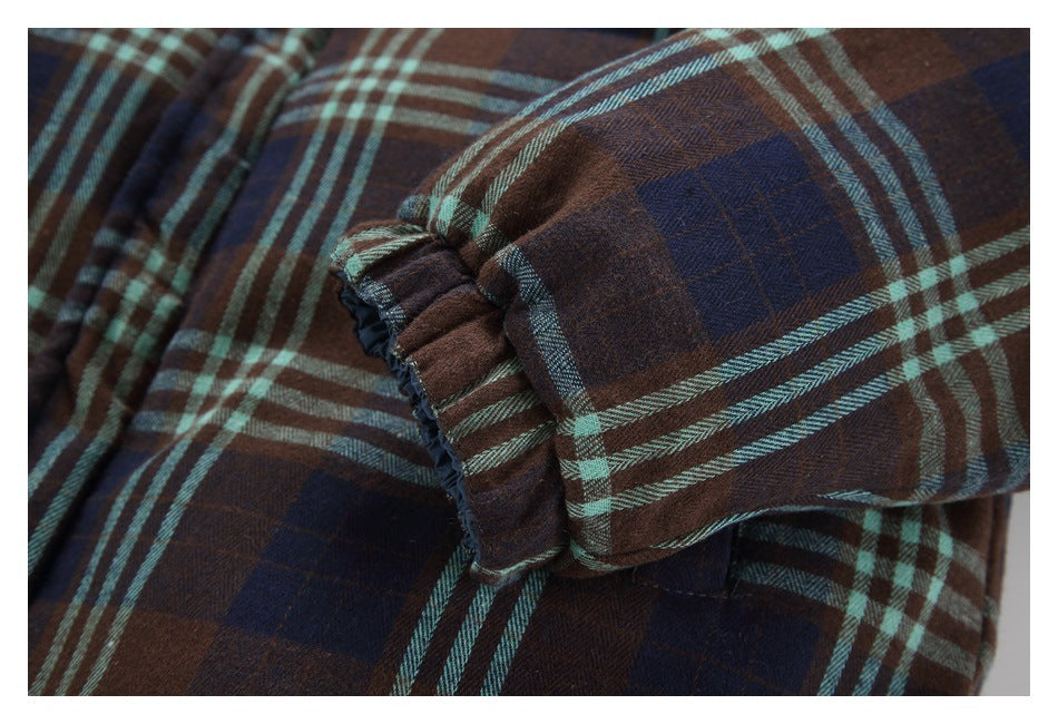Close-up of a gathered cuff on brown and navy plaid fabric with pale aqua stripes.