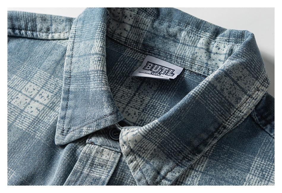 Close-up of a blue and gray patterned denim shirt collar, dark button, and sewn-in neck label.