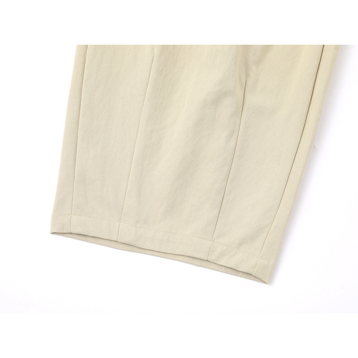 Close-up of the cream trousers' stitched hem and panel seams.