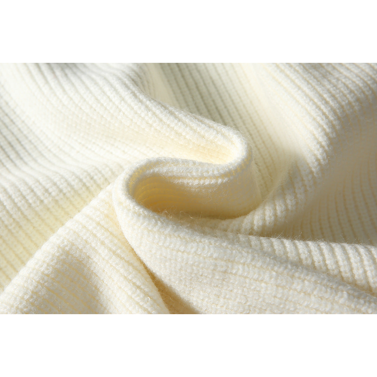 Close-up of the ivory sweater's ribbed knit, folded to show the fabric texture.