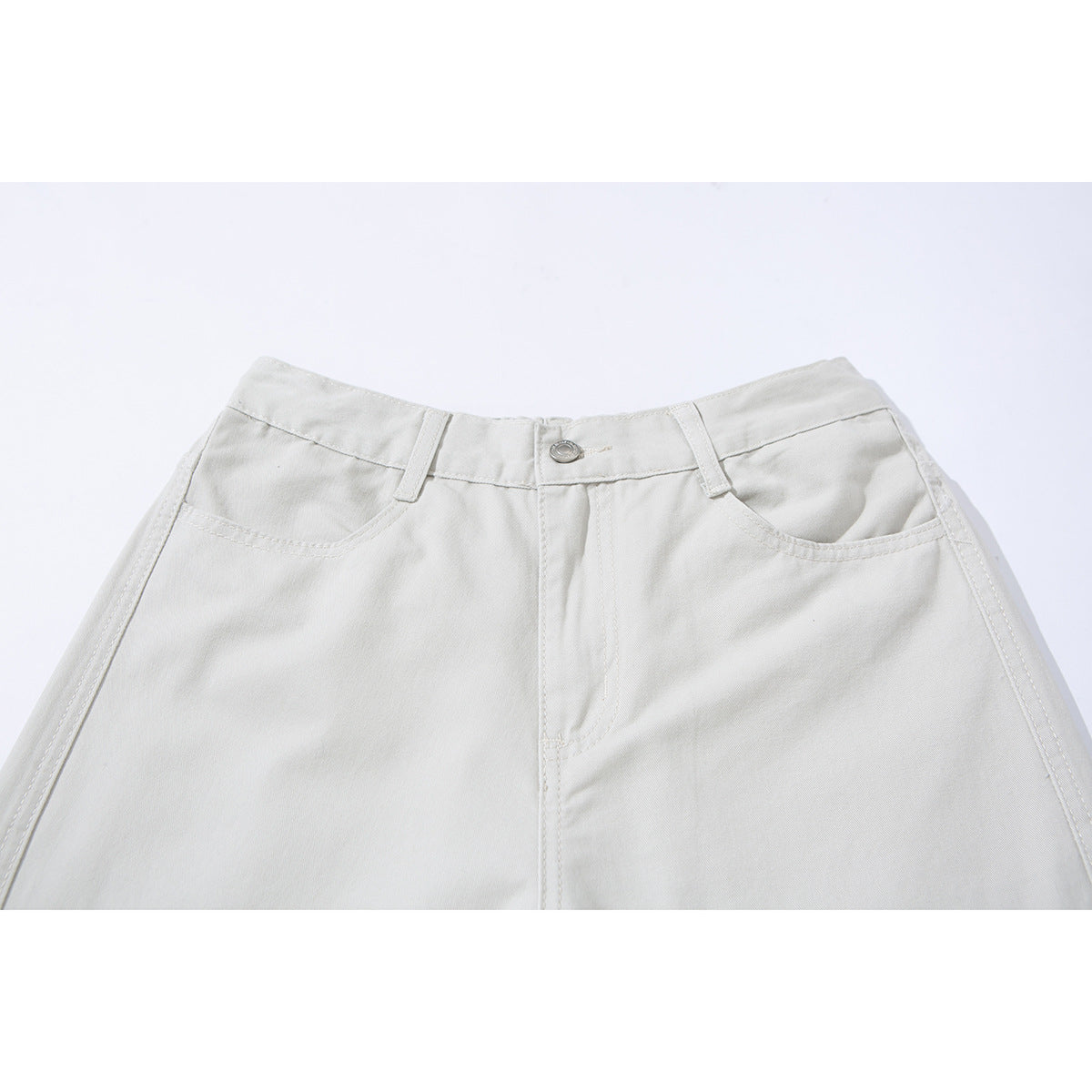 Close-up of ivory wide-leg trousers showing the front waistband, button, belt loops, and curved pockets.