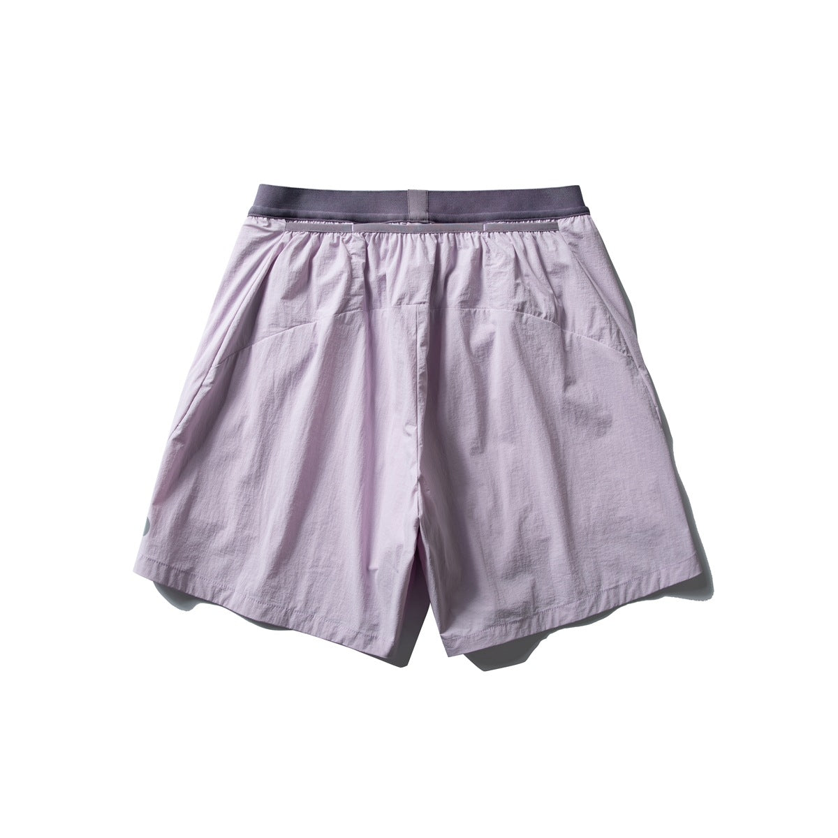Back view of loose light-lilac shorts with a dark charcoal waistband and wide legs, laid flat on white.