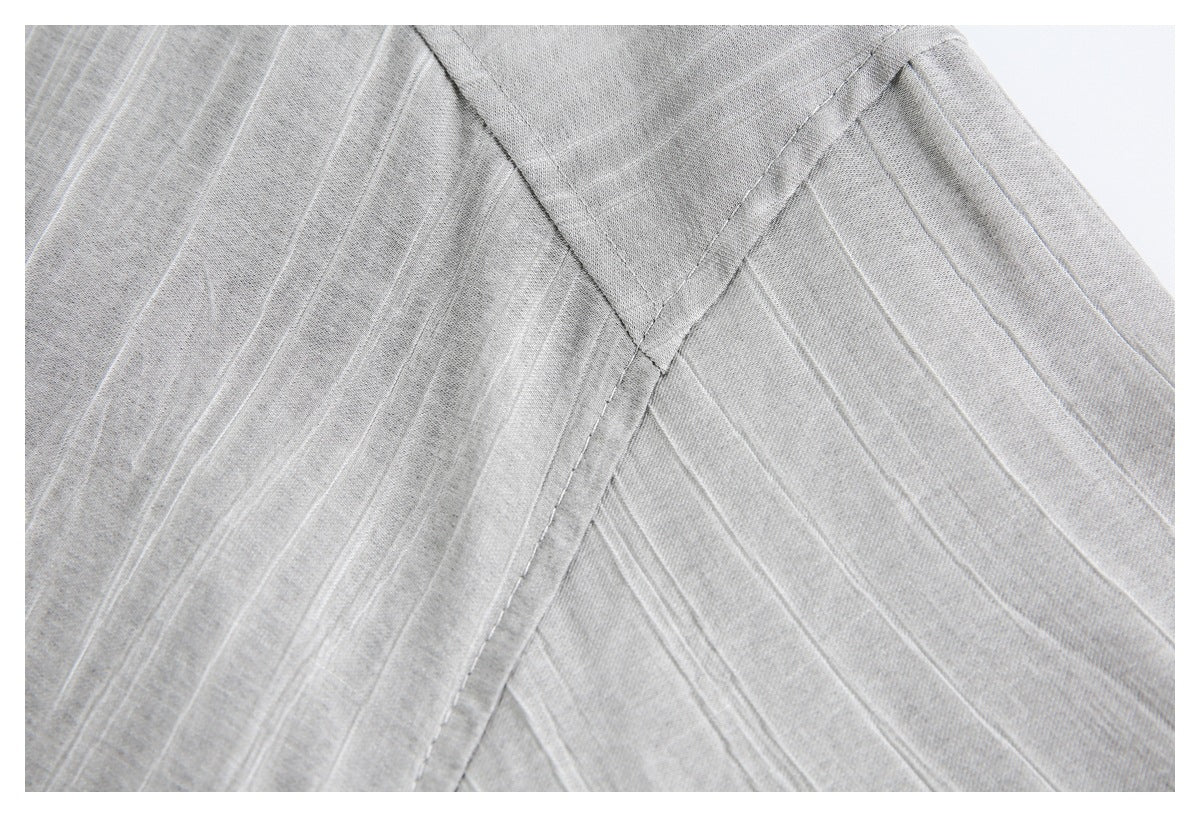 Close-up of intersecting seams and raised linear texture on gray garment fabric.