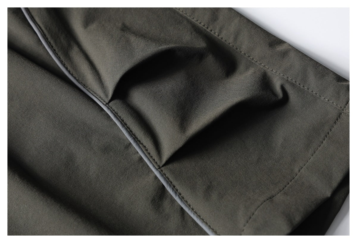 Close-up of dark olive pants showing a stitched pocket edge and fabric seams.