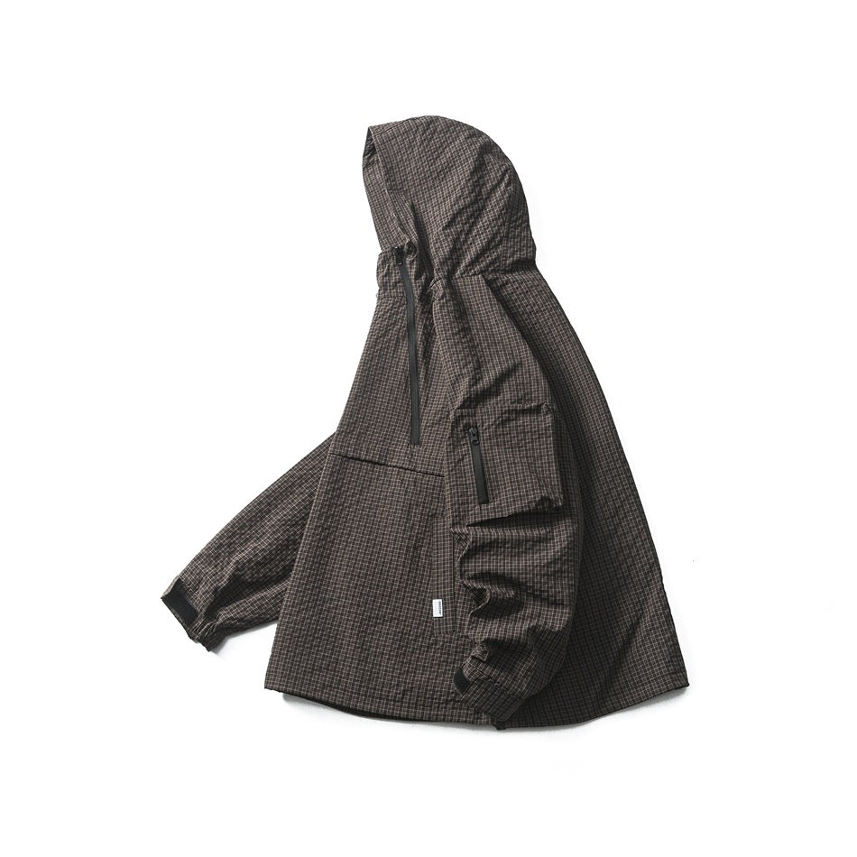 Angled front view of a dark brown grid-pattern hooded pullover jacket with a front pocket and zippered sleeve pocket.