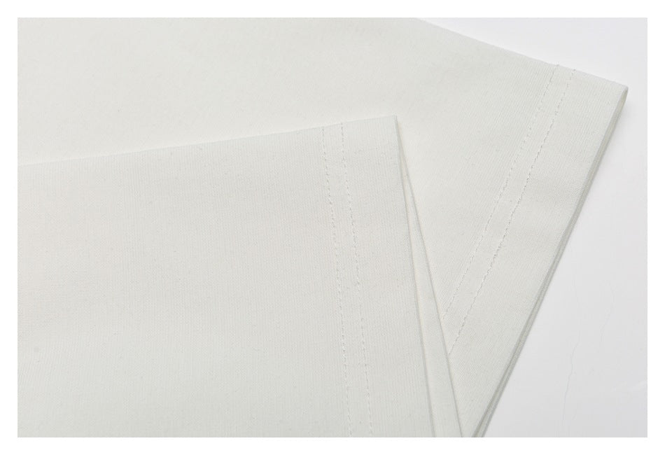 Close-up of the sleeve and hem stitching on an off-white T-shirt.